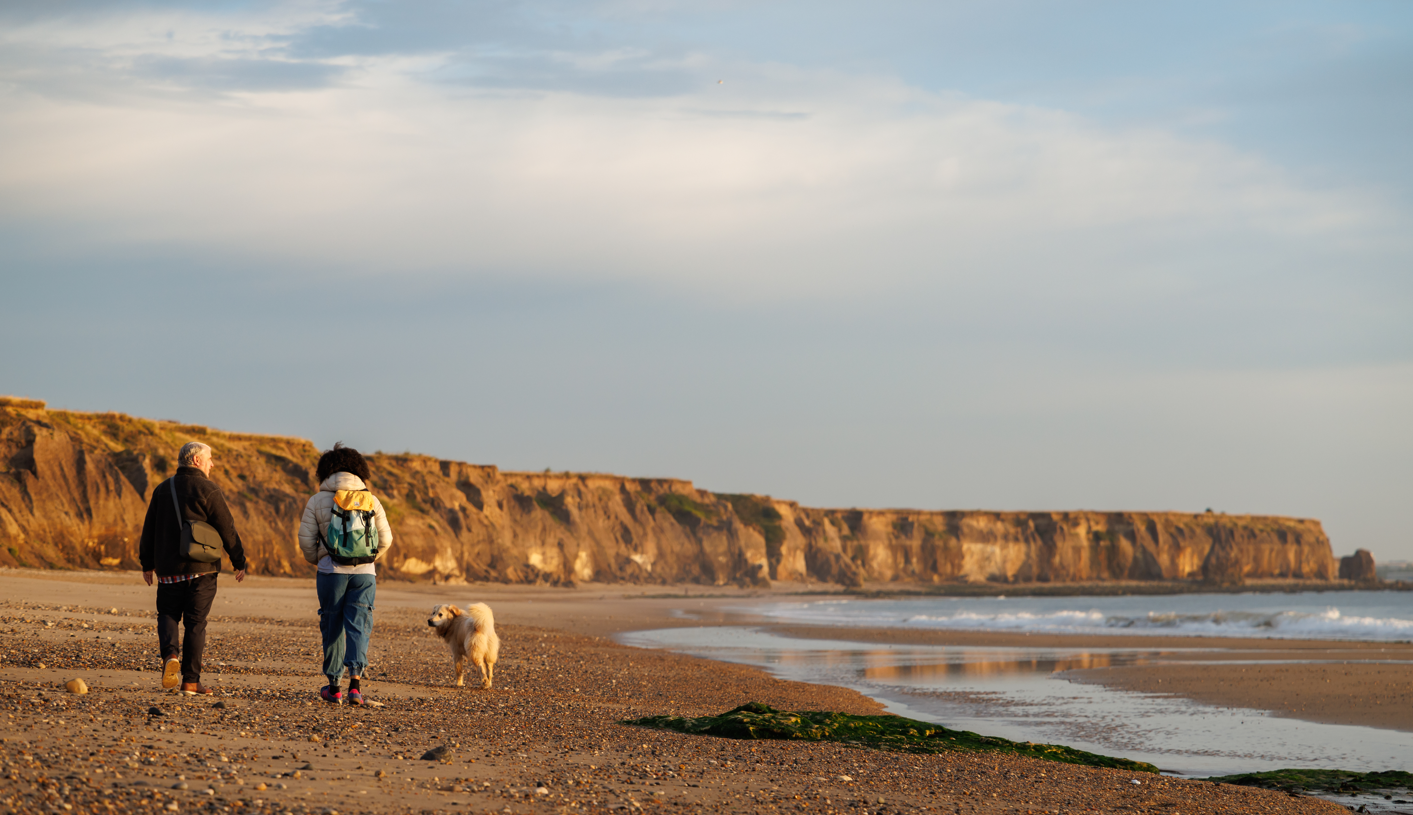 Two people and their dog walking along Seaham Beach