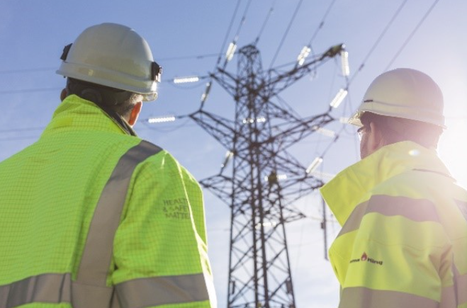 Workers in PPE with transmission towers