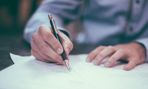 Photo of someone signing a piece of paper