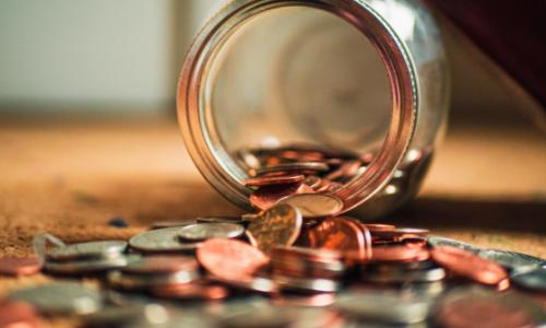 Photo of coins spilling out of a glass jar