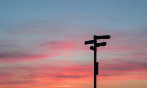 Photo of a signpost in front of a sunset